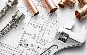 Copper fittings and wrench on plumbing blueprints